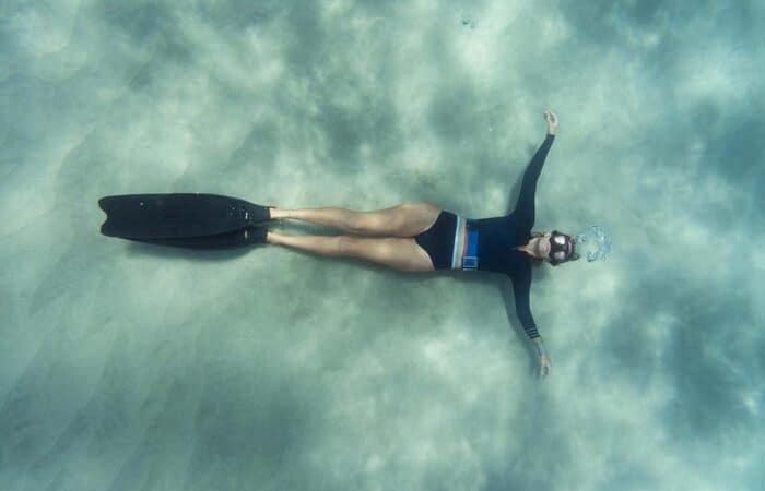 Kobieta freediver leżąca na piaszczystym dnie